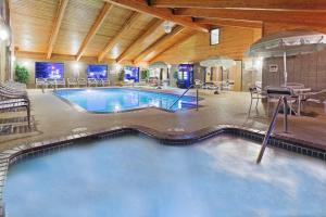 a swimming pool in a building with a table and chairs at AmericInn by Wyndham Bemidji in Bemidji