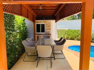 un patio con tavolo, sedie e piscina di Saransiri - 3 bedroom villa with private pool, office room & fast Wi-fi a Phuket