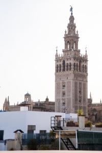 um edifício alto com uma torre de relógio em cima em Guzman El Bueno Suites em Sevilha