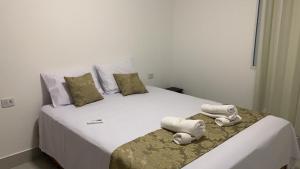 a bedroom with a large white bed with towels on it at Flats Solares in São Miguel dos Milagres