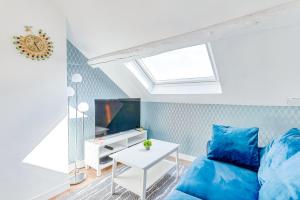 a living room with a blue couch and a tv at Escale pro & détente à 3 min de la gare - Parking - WIFI - PS4 in Corbeil-Essonnes