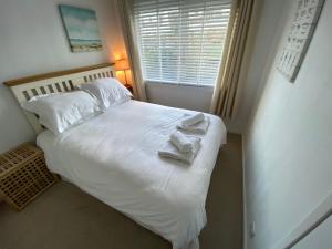 Un dormitorio con una cama blanca con toallas. en Beach View Cottage, en Isle of Gigha