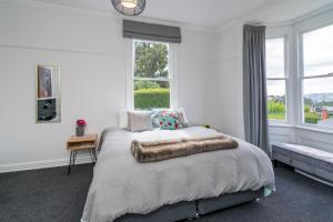 a white bedroom with a bed with a blanket on it at Magic in Mornington in Dunedin