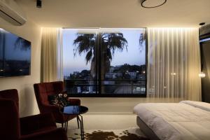 a bedroom with a bed and a chair and a window at Urbanica Carmel- Apartments in Haifa