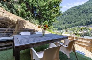 a wooden table with chairs and a vase of flowers at Alpine Retreat in Queenstown