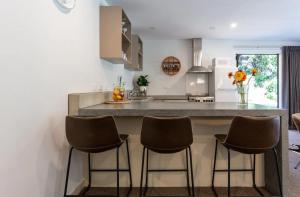 a kitchen with a counter with four bar stools at Alpine Retreat in Queenstown