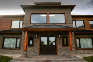 uma casa com uma porta preta e janelas em Senderos Aparts & Suites em El Chaltén