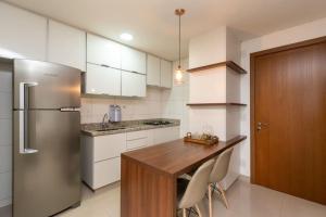 a kitchen with a wooden table and a refrigerator at Lindo Studio no Setor Bueno - Edifício The Expression - Vista Piscina - WIfi - TH304 in Goiânia