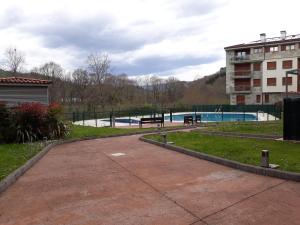 a park with a pool and benches and a building at Apartamento La Esperanza in Cangas de Onís