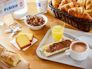 einen Tisch mit einem Teller Gebäck und einer Tasse Kaffee in der Unterkunft Ibis Budget Cergy St Christophe in Cergy