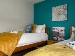 2 camas en una habitación con paredes azules en King Court Apartment, en Motherwell