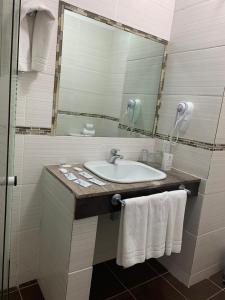 a bathroom with a sink and a mirror and towels at Punta del Este Shelton Hotel in Punta del Este