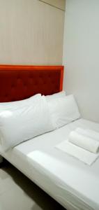 Bett mit weißer Bettwäsche und einem Kopfteil aus Holz in der Unterkunft Chin's Place Sea Residences MOA in Manila