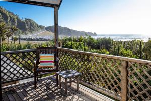 einen Stuhl auf einer Veranda mit Blick auf den Strand in der Unterkunft Seascapes in Punakaiki