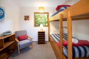 a bedroom with bunk beds with a chair and a desk at Seascapes in Punakaiki