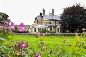 a house in a field with flowers in the foreground at Nydsley Hall by Luxury Travel Emproium - 4 Luxury Apartments - 2 with Hot Tubs in Pateley Bridge