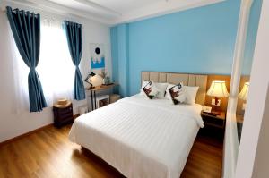 - une chambre avec un grand lit blanc et des rideaux bleus dans l'établissement Sogo Hotel Saigon, à Hô-Chi-Minh-Ville