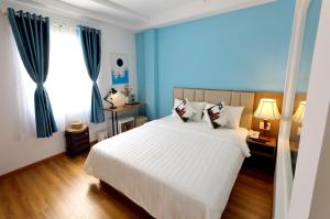 a bedroom with a large white bed and blue curtains at Sogo Hotel Saigon in Ho Chi Minh City