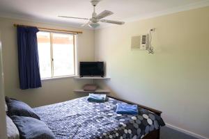 a bedroom with a bed and a tv and a window at Lancelin Lodge in Lancelin