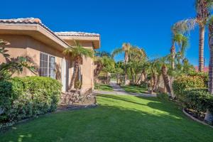 a house with palm trees and a green lawn at Swan House in Palm Springs