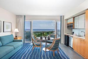 Ala Moana Hotel - Resort Fee Included في هونولولو: غرفة معيشة مع أريكة وطاولة مع كراسي