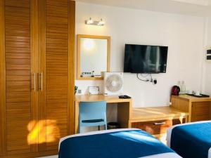 a bedroom with a desk and a tv and a bed at Reef Edge Thulusdhoo, Maldives in Thulusdhoo