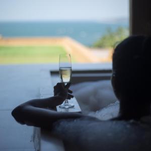 a woman holding a glass of wine in front of a window at Red Thread Vagator in Vagator