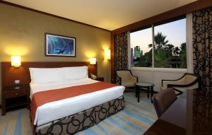 ein Hotelzimmer mit einem Bett und einem großen Fenster in der Unterkunft Holiday Inn Riyadh Izdihar, an IHG Hotel in Riad