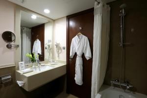 a bathroom with a sink and a shower and a robe at Holiday Inn Riyadh Izdihar, an IHG Hotel in Riyadh