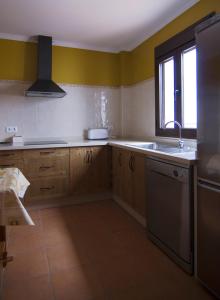 cocina con armarios de madera, fregadero y ventana en Casa Concepción en Grazalema