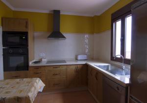 uma cozinha com paredes amarelas, armários de madeira e um lavatório. em Casa Concepción em Grazalema