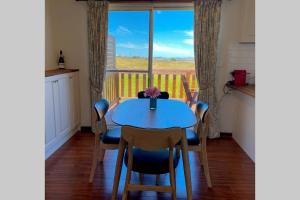 een eetkamer met een blauwe tafel en stoelen en een raam bij Karinya Beach House in Corinella