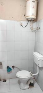 a white bathroom with a toilet and a light on the wall at Vamoose Balaji Inn in Hoshangābād