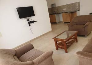a living room with a couch and a table and a tv at Areia De Goa - Sunrise By Leela Homes in Arpora