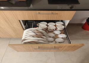 a drawer filled with cups and plates in a kitchen at Areia De Goa - Sunrise By Leela Homes in Arpora