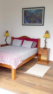 a bedroom with a bed with two lamps and a table at Honey Moon - Vista do mar na cama. in Caraguatatuba