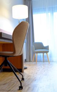 a chair sitting next to a desk with a lamp at Hotel am Kloster in Werne an der Lippe