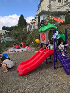 eine Gruppe von Kindern, die auf einem Spielplatz spielen in der Unterkunft 清境花鳥蟲鳴高山露營區 in Jen-chuang