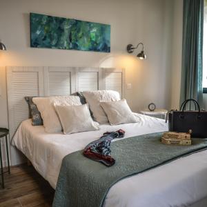 1 dormitorio con 1 cama grande con sábanas y almohadas blancas en Domaine de Sévanes, en Saint-Paul-les-Fonts