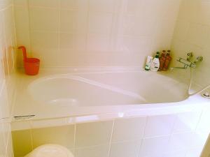 a white bath tub in a bathroom with a toilet at Guest House Miyakojima in Miyako-jima