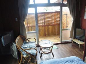 a room with a balcony with a table and chairs at Guest House Miyakojima in Miyako-jima