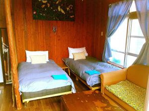 a room with two beds and a couch and a window at Guest House Miyakojima in Miyako-jima