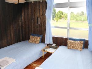 two beds in a room with a window at Guest House Miyakojima in Miyako-jima