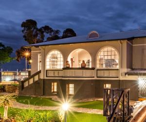 a large white house with people sitting on the balcony at Haus Schwerinsburg Guest House in Windhoek