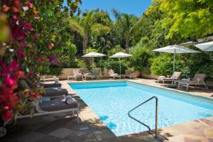a swimming pool with lounge chairs and umbrellas at Last Word Constantia in Cape Town