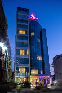 a tall glass building with a neon sign on it at Grand Palace Hotel & Resorts Sylhet in Sylhet