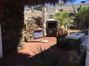 un patio avec un parasol et un bâtiment en pierre dans l'établissement Cactus b&b Le casette di Marilena, à Pantelleria