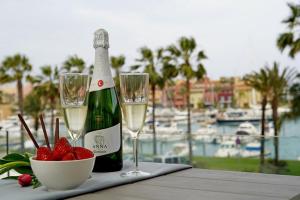 Una botella de champán y dos copas en una mesa con fresas. en NEW & Modern Apartment - Marina, Sotogrande, en Sotogrande