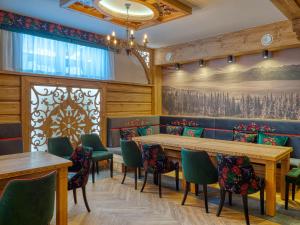 a dining room with wooden tables and green chairs at Dom Wypoczynkowy U Chramca in Białka Tatrzanska