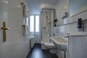 a white bathroom with a sink and a toilet at Central Hotel am Dom - Köln City in Cologne